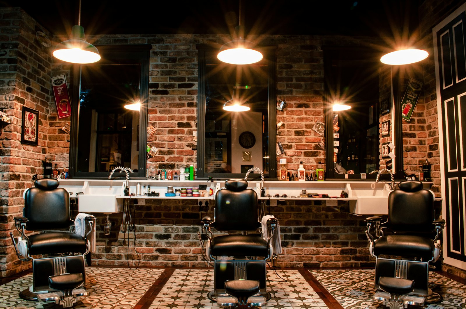 Interior Gentleman's Cut dengan dinding bata, lampu gantung dan kursi barber klasik