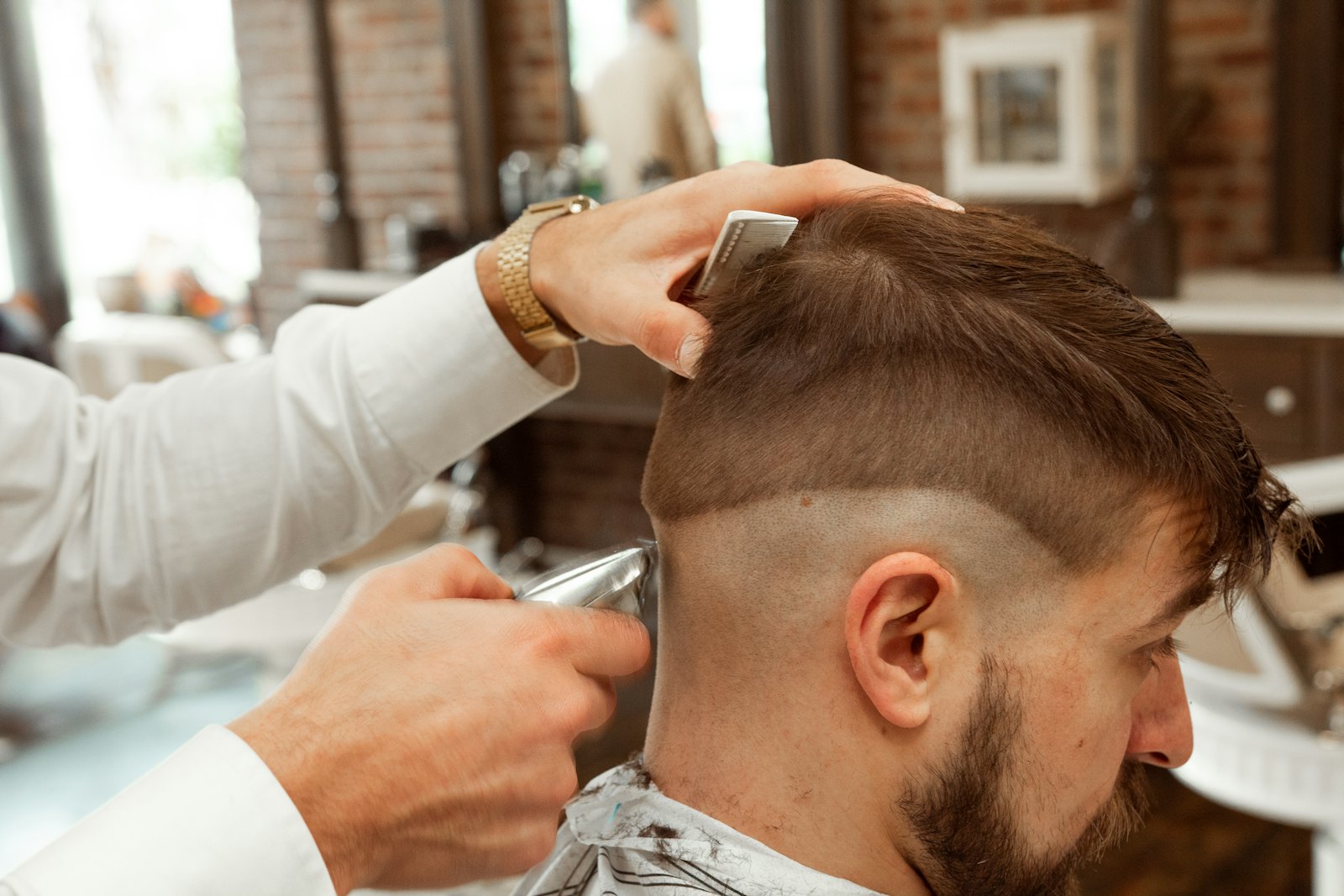 Barber merapikan potongan fade pelanggan dengan clipper