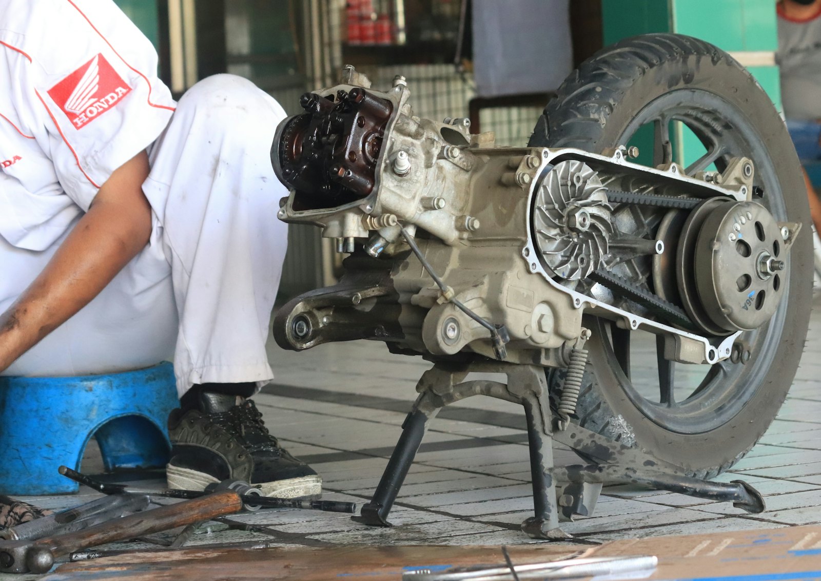 Mekanik membongkar mesin dan CVT skuter di bengkel